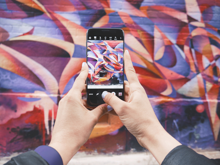 photo of someone taking a photo of a colorful wall with a smartphone
